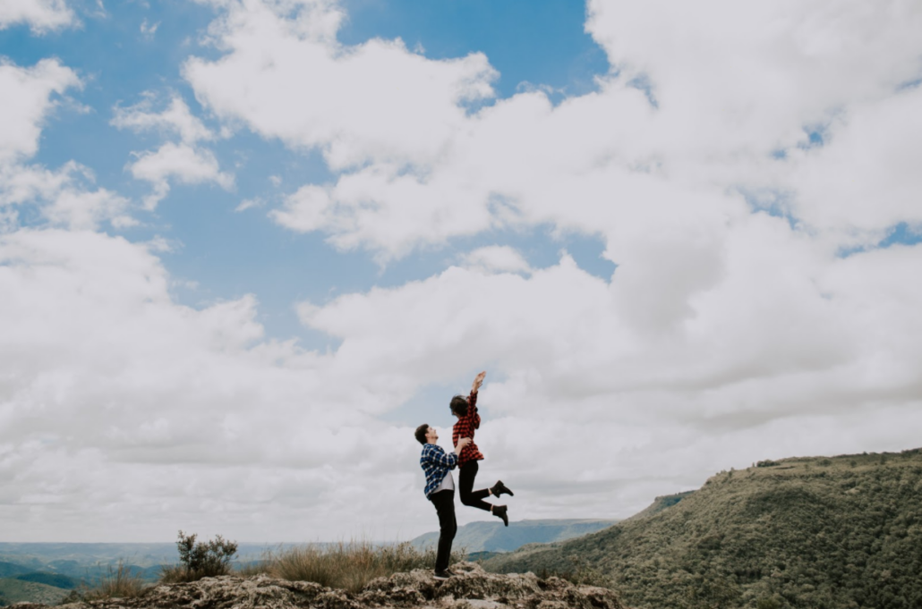 Man and woman smiling and jumping on mountain sexual health